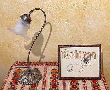 Creativity: ©S.L.Reay photograph of a lamp, embroidered table cover, and a framed hand-drawn restroom sign with an arrow and a crow ©DebEwing